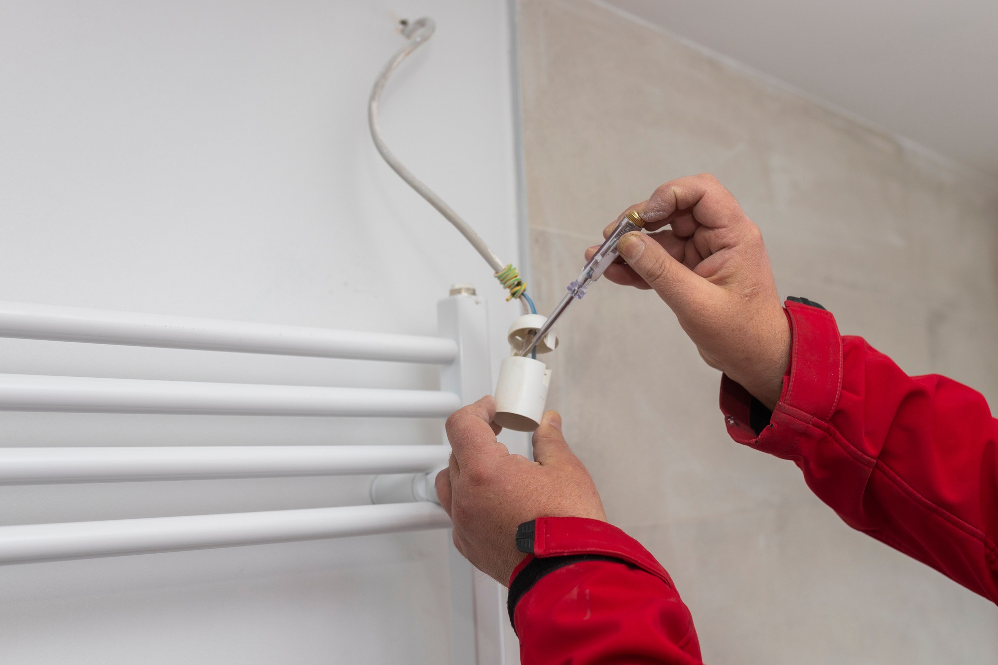 Skilled tradesman performing electrical maintenance on a white wall